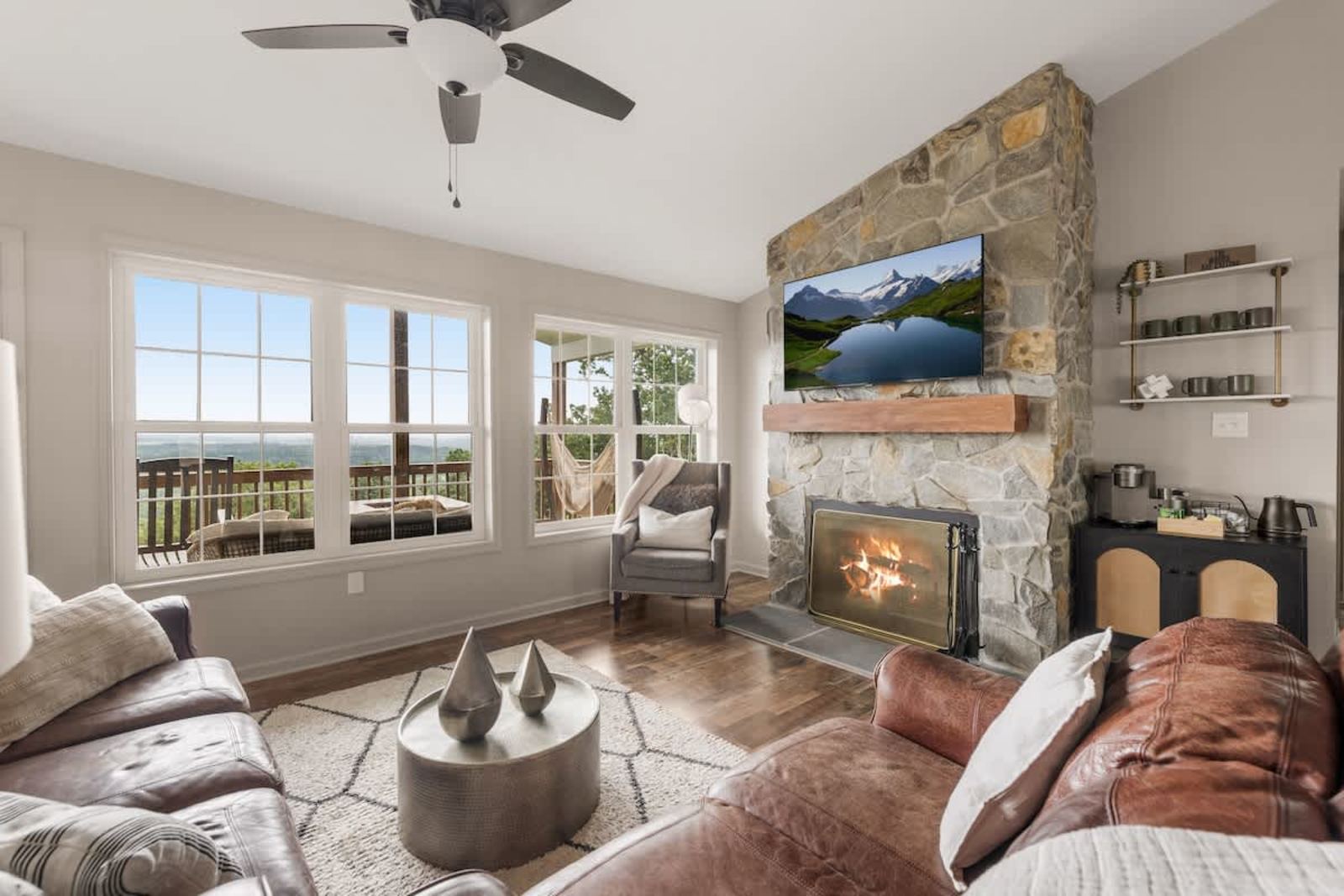 Vaulted living room with a stone fireplace and a valley view through wide windows